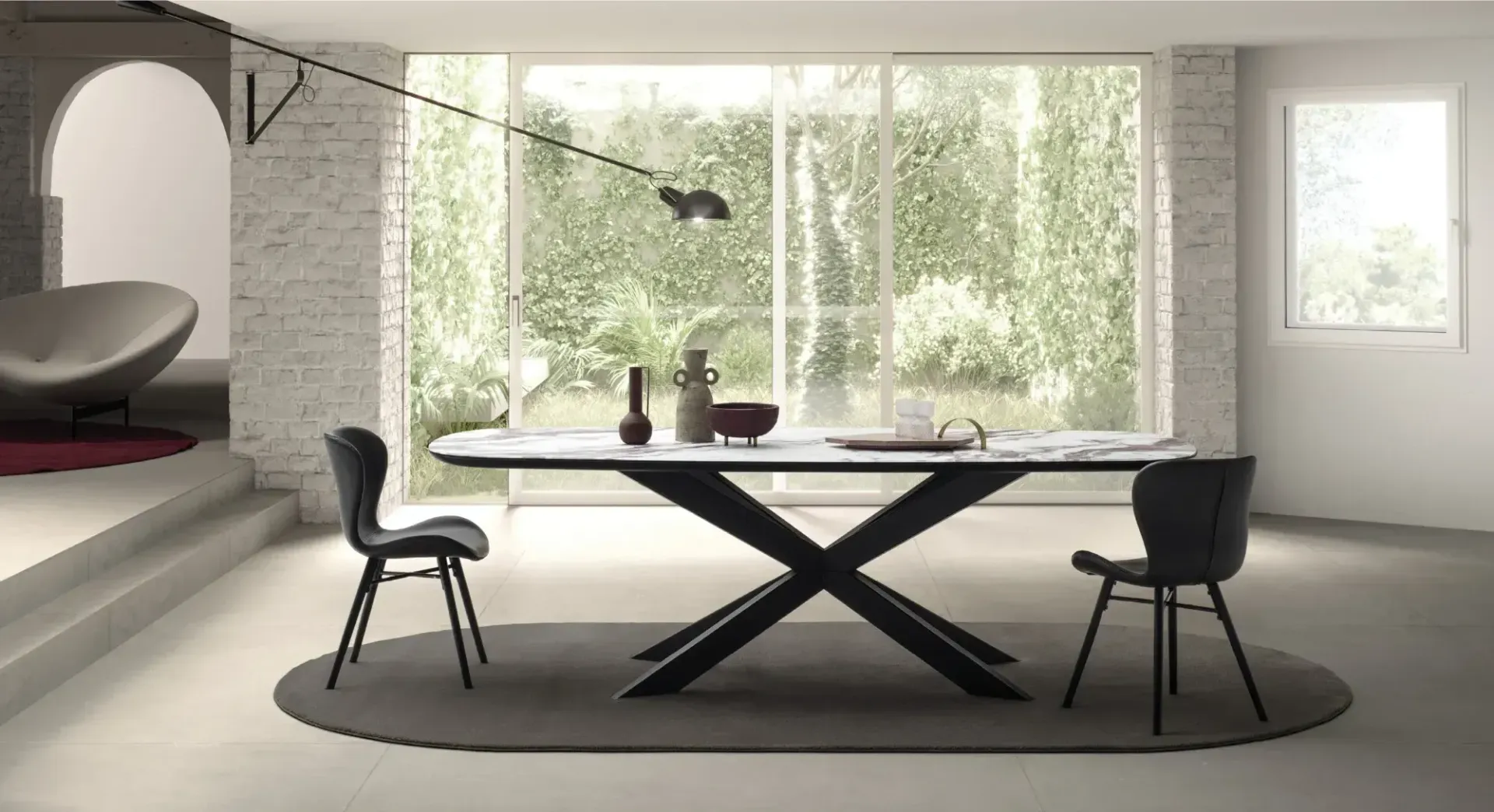 Sala da pranzo moderna con tavolo nero, due sedie, ampie finestre e un morbido tappeto ovale.