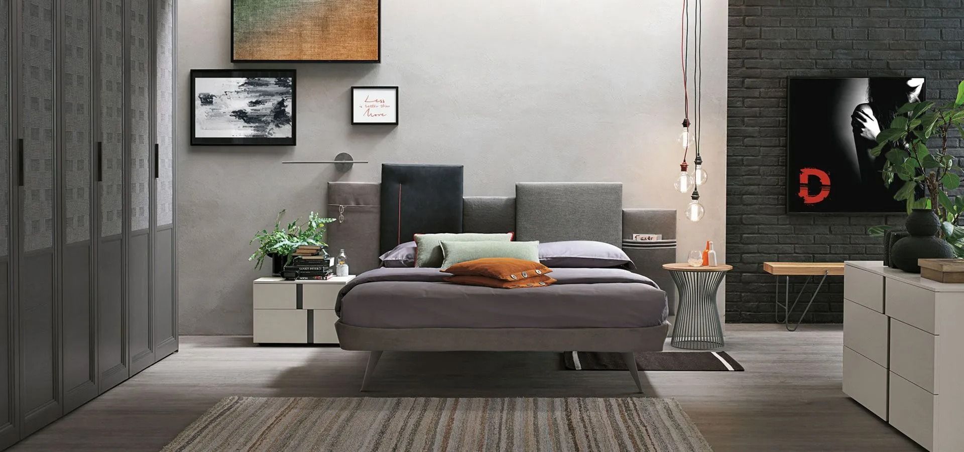 Camera da letto moderna sui toni del grigio con letto basso, quadri alle pareti, piante e un camino acceso sulla destra.