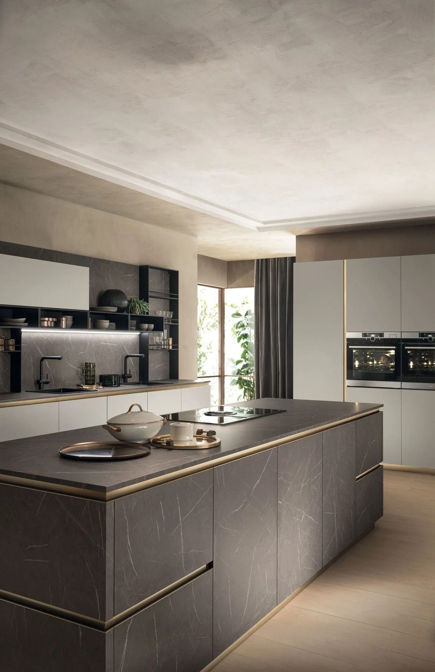 Cucina moderna con grande isola scura, mensole a vista e forni a incasso accanto a una finestra luminosa