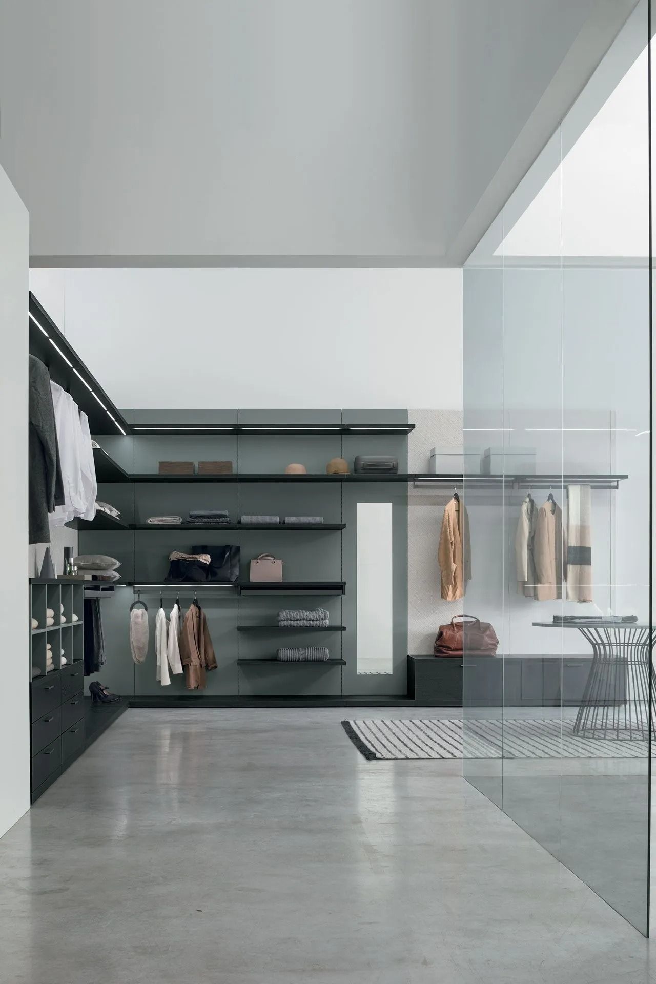 Negozio di abbigliamento moderno e minimalista con scaffalature nere, capi appesi e pavimento in cemento lucidato.