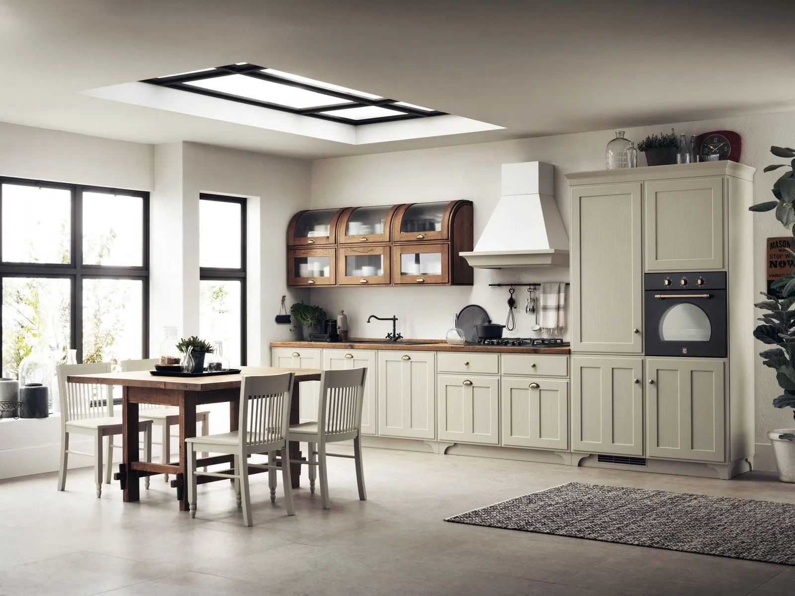 Luminosa cucina-sala da pranzo moderna con mobili bianchi, tavolo in legno, ampie finestre e tappeto a motivi geometrici.