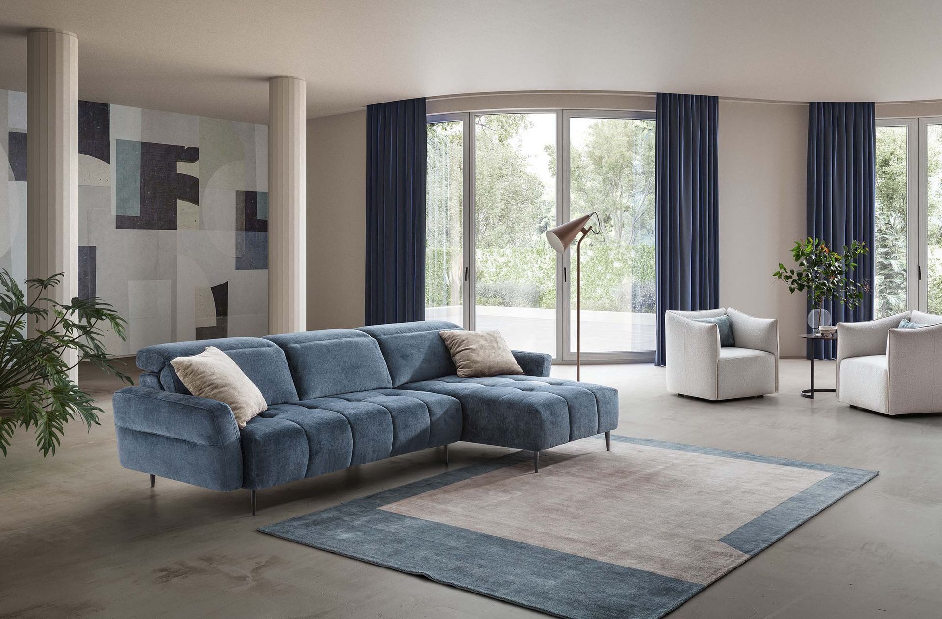 Luminoso soggiorno moderno con divano angolare blu, tappeto, poltrone, ampie finestre e piante da interno.