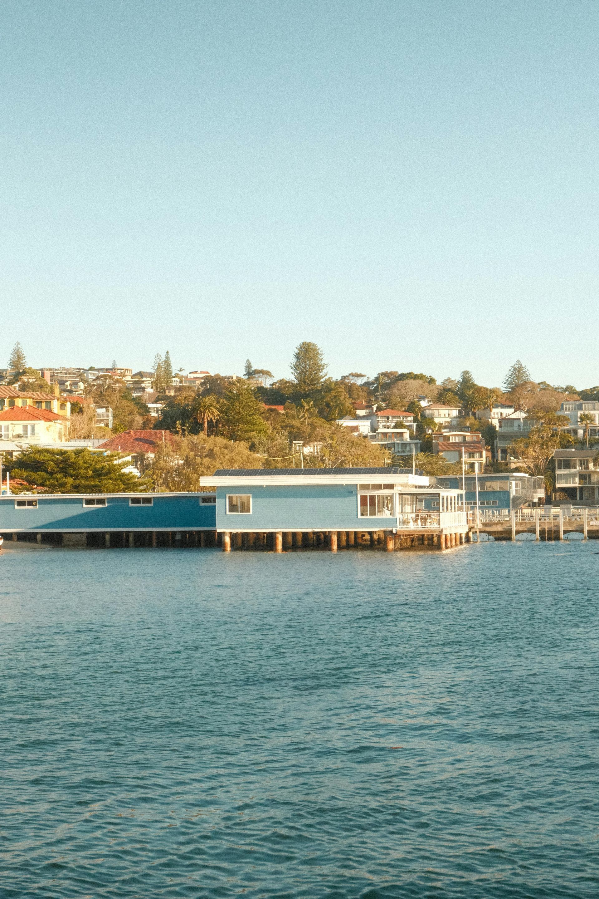 Waterfront homes and a docked boat along a calm bay under a clear sky