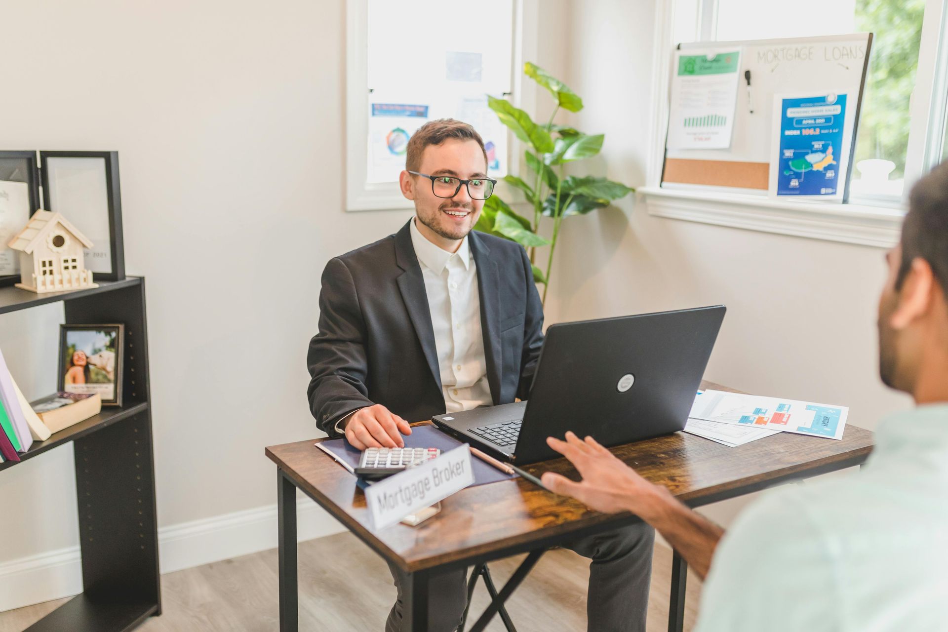 Consultation desk with a smiling man in glasses meeting a person across a laptop