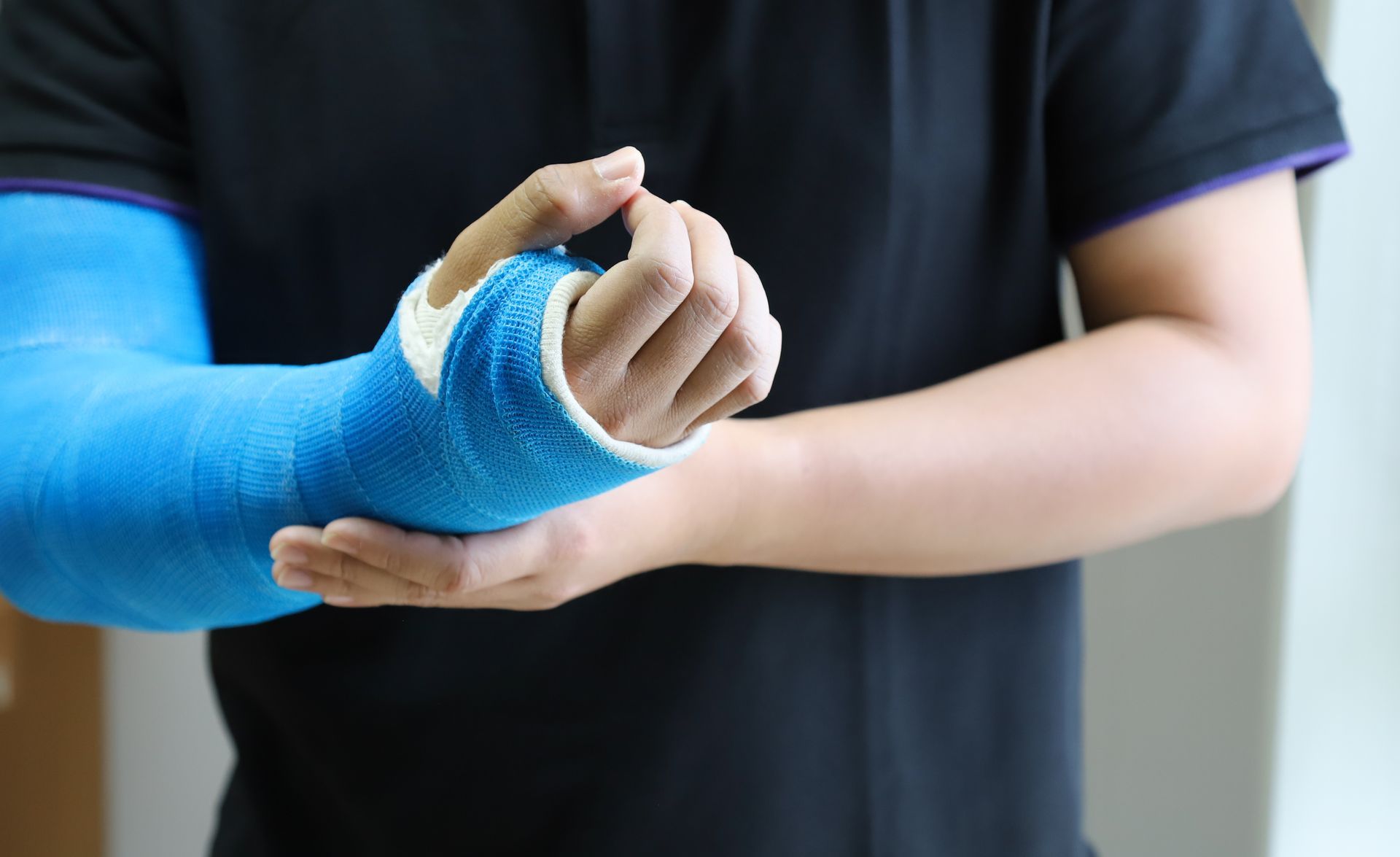 A man with a blue cast on his arm is holding his hand.