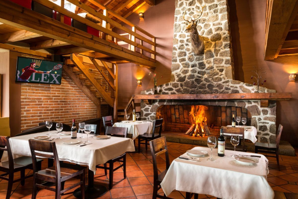 A restaurant with tables and chairs and a fireplace