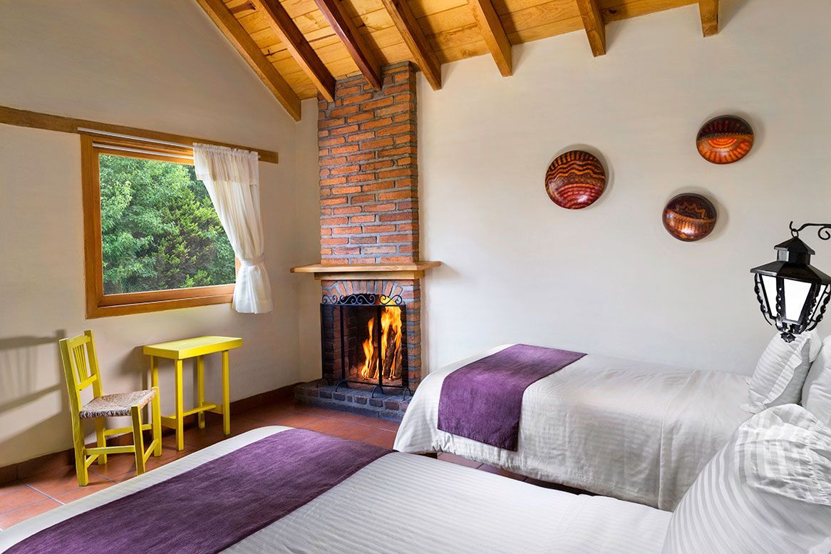 A bedroom with two beds and a fireplace.