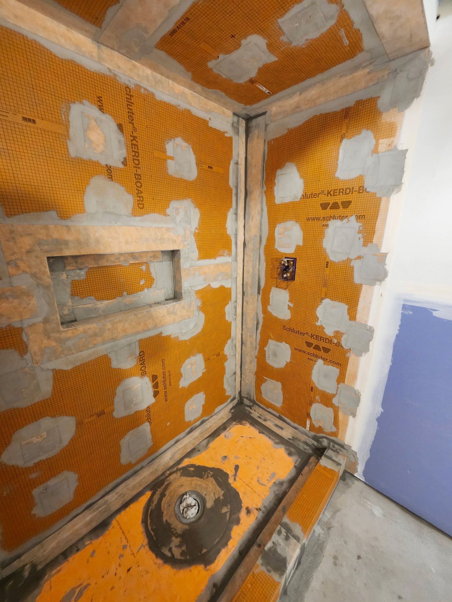 Membrane d'étanchéité orange installée dans la douche, prête à recevoir le carrelage.