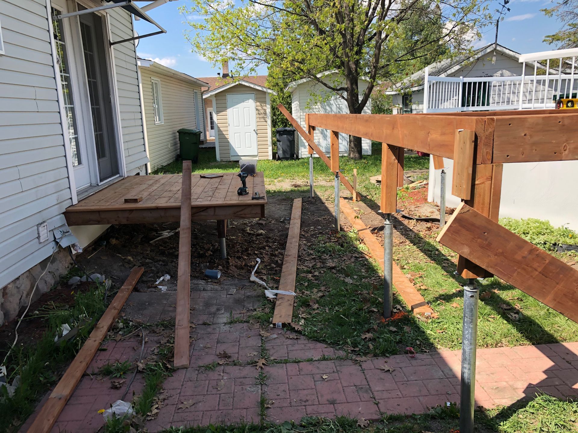 Construction d'une terrasse : structure en bois brun, supports et planches dans une cour arrière.