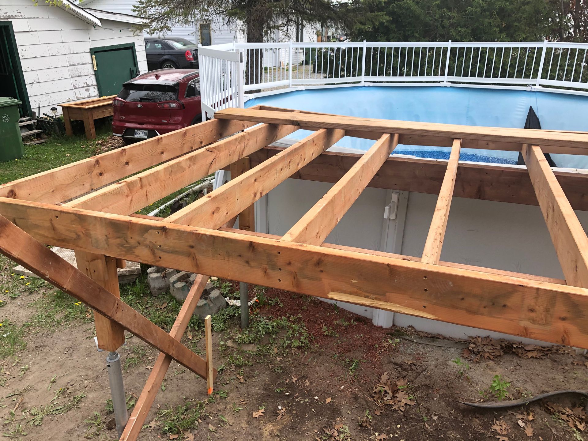 Construction d'une structure de terrasse en bois à côté d'une piscine hors sol bleue.