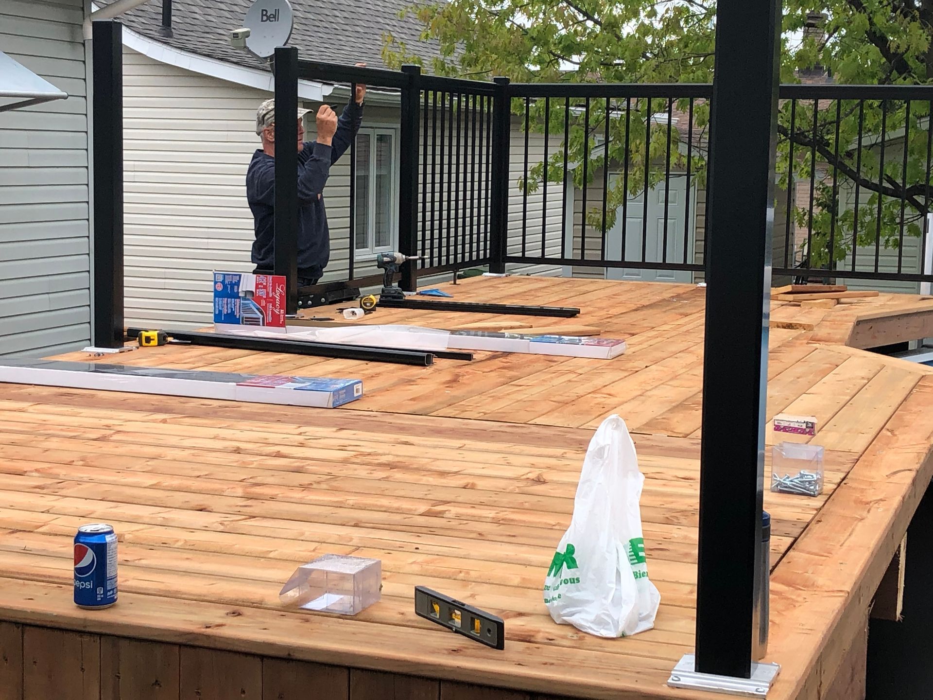 Une personne installe une rambarde noire sur une terrasse en bois nouvellement construite.