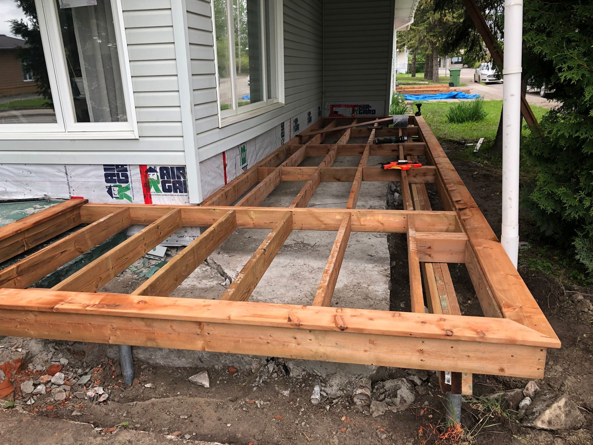 Construction d'une structure de terrasse en bois à l'extérieur d'une maison au bardage gris.