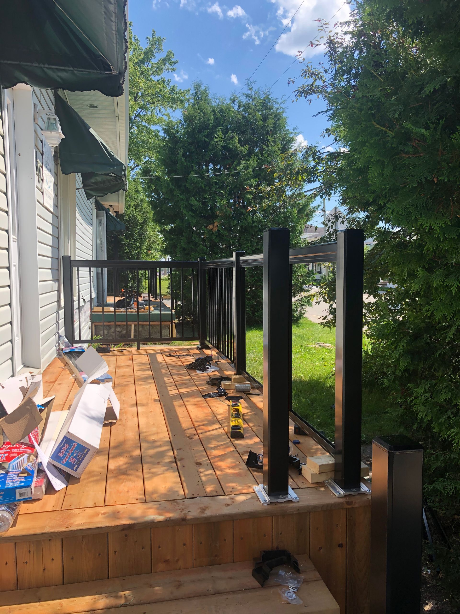 Construction d'une terrasse avec poteaux de garde-corps noirs et panneaux de verre.