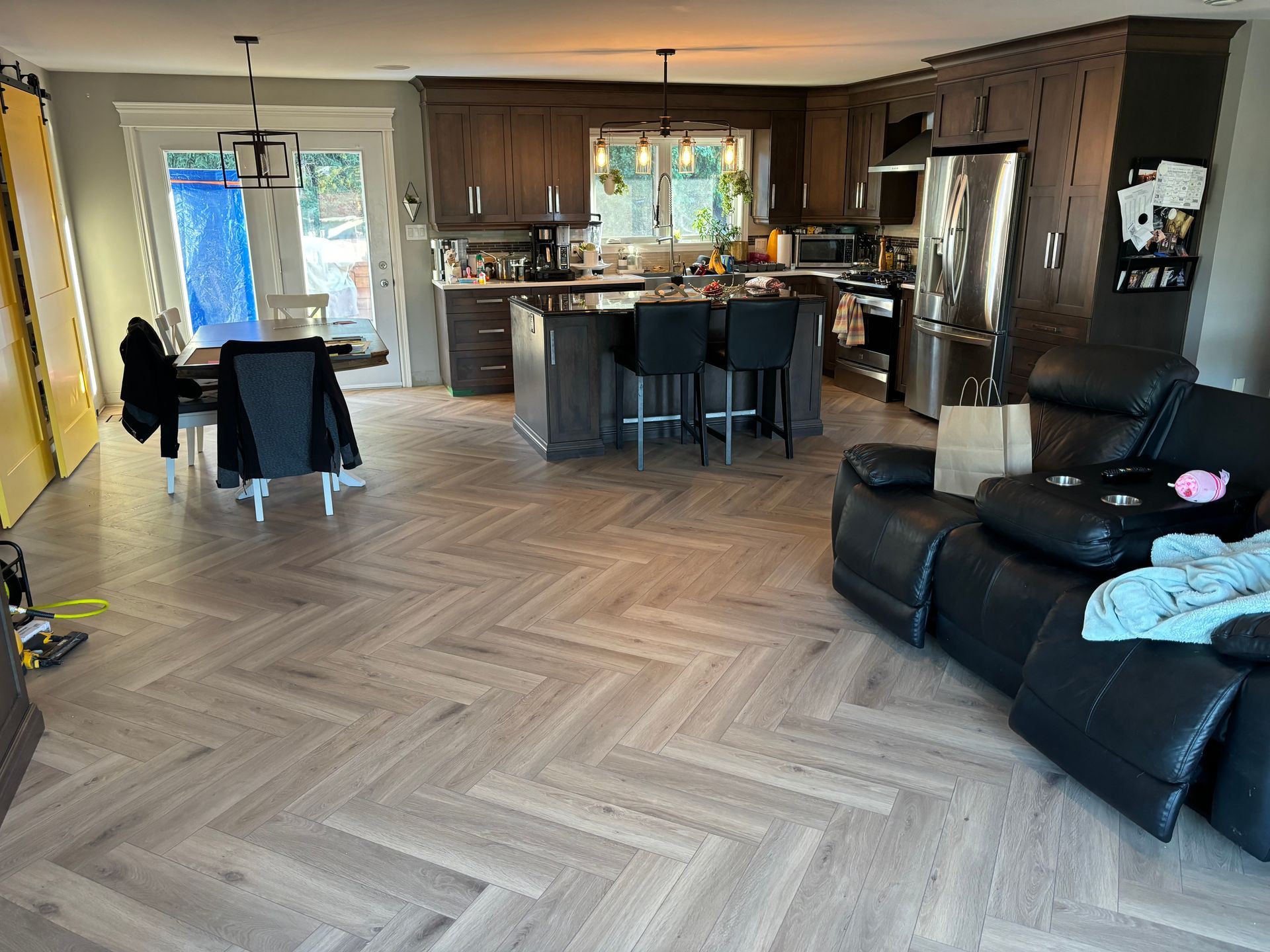 Cuisine et salle à manger avec placards en bois foncé, îlot central et parquet à chevrons.