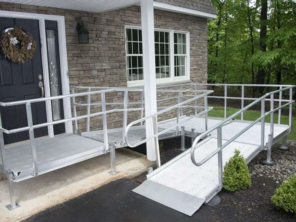 Accessible front entrance with white ramp and railings leading to a brick house porch