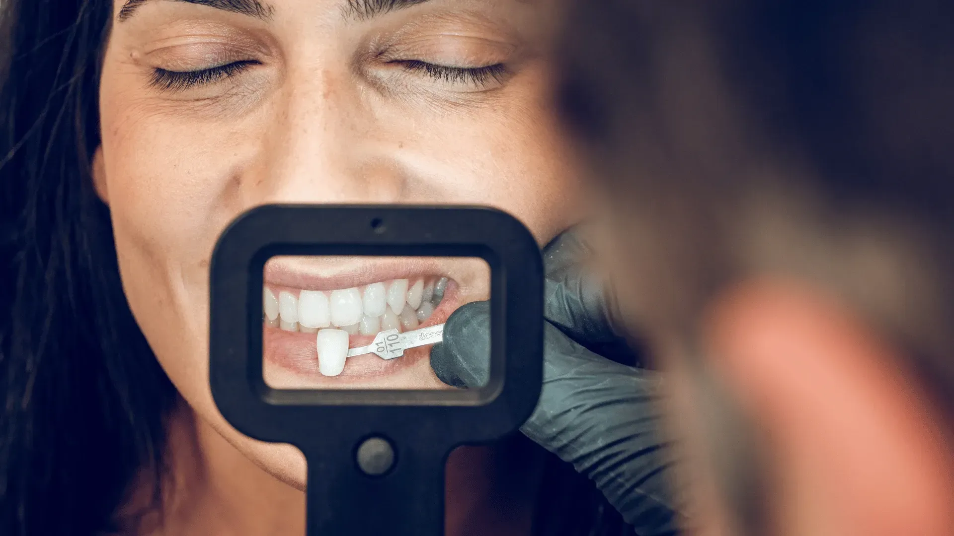A woman is looking at her teeth through a magnifying glass.