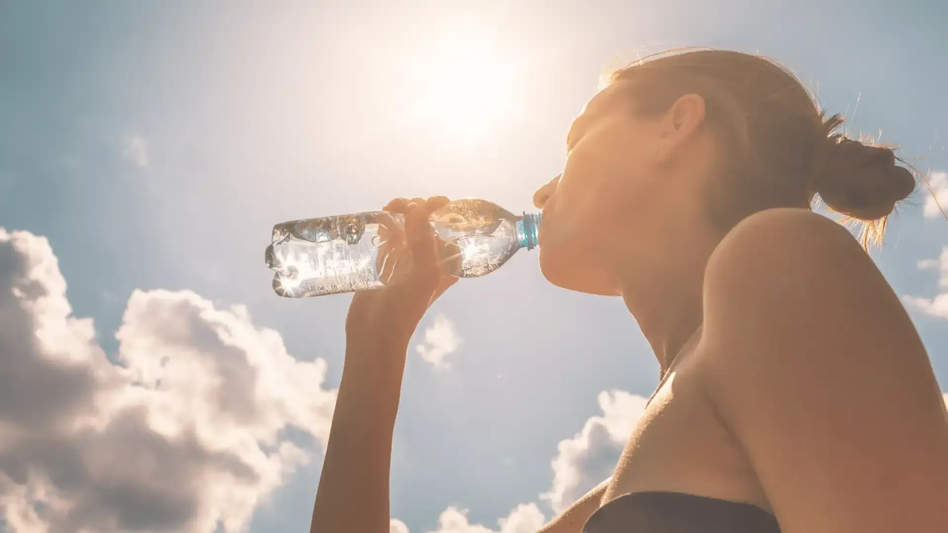 a woman drinks water from a plastic bottle