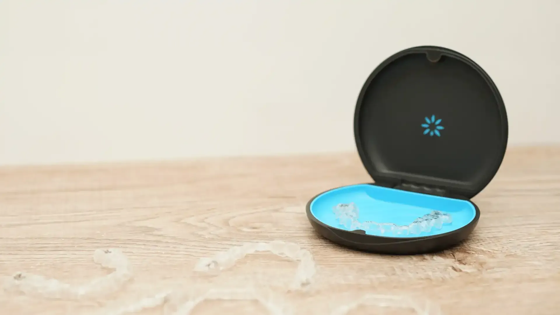 An invisalign case is sitting on a wooden table.
