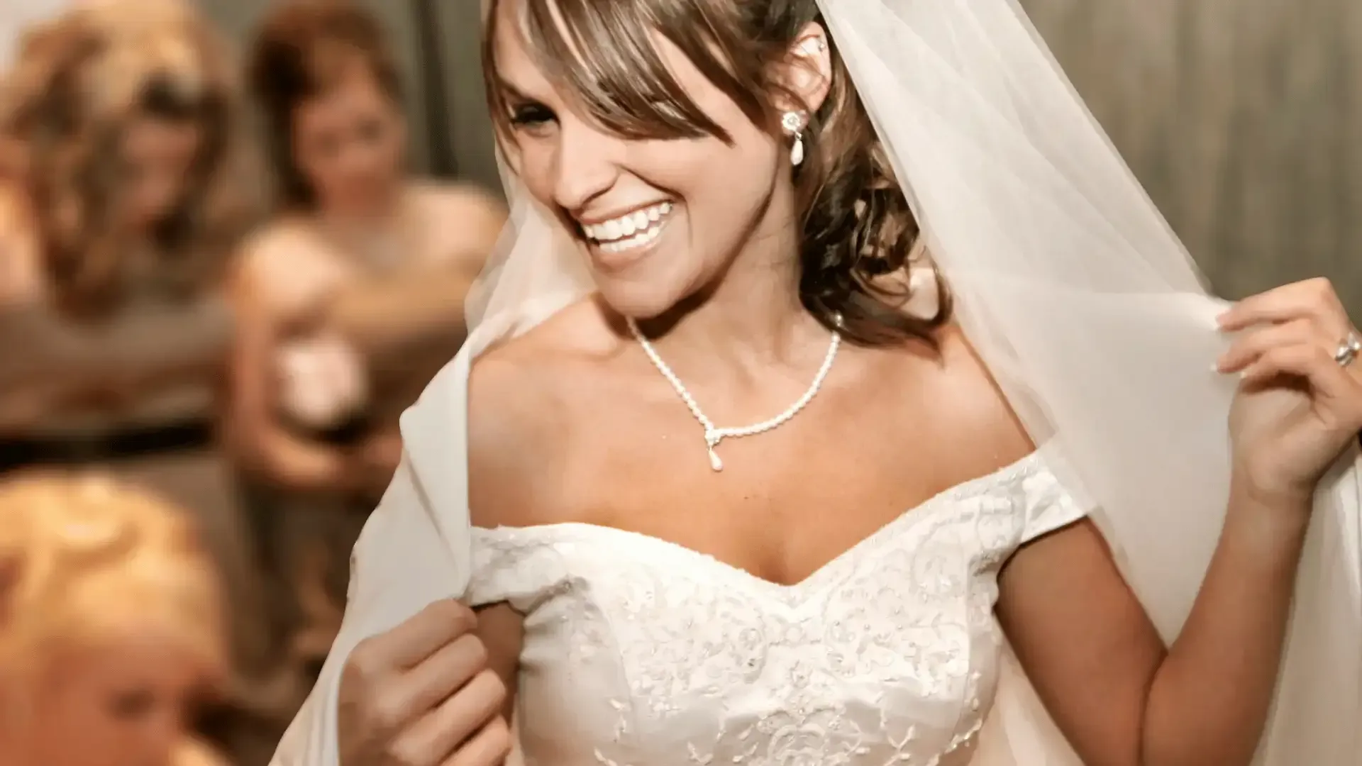 A woman in a wedding dress and veil is smiling