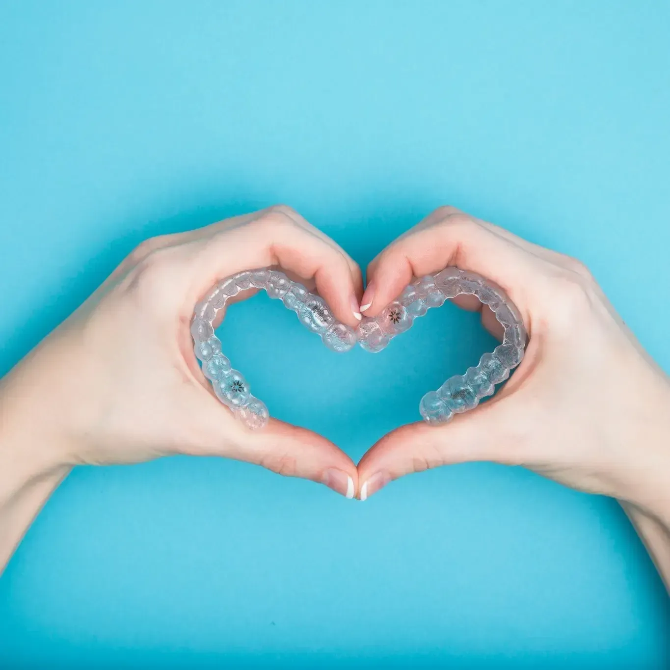 A woman is making a heart shape with her hands.
