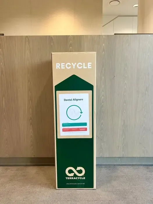 Tall green recycling bin with white “RECYCLE” sign in a hallway.