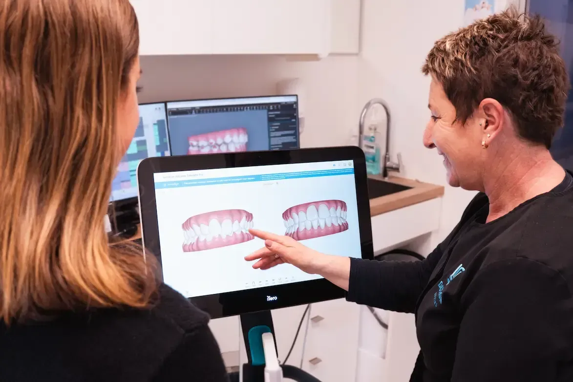 Two people reviewing a dental scan on a computer screen in a clinic