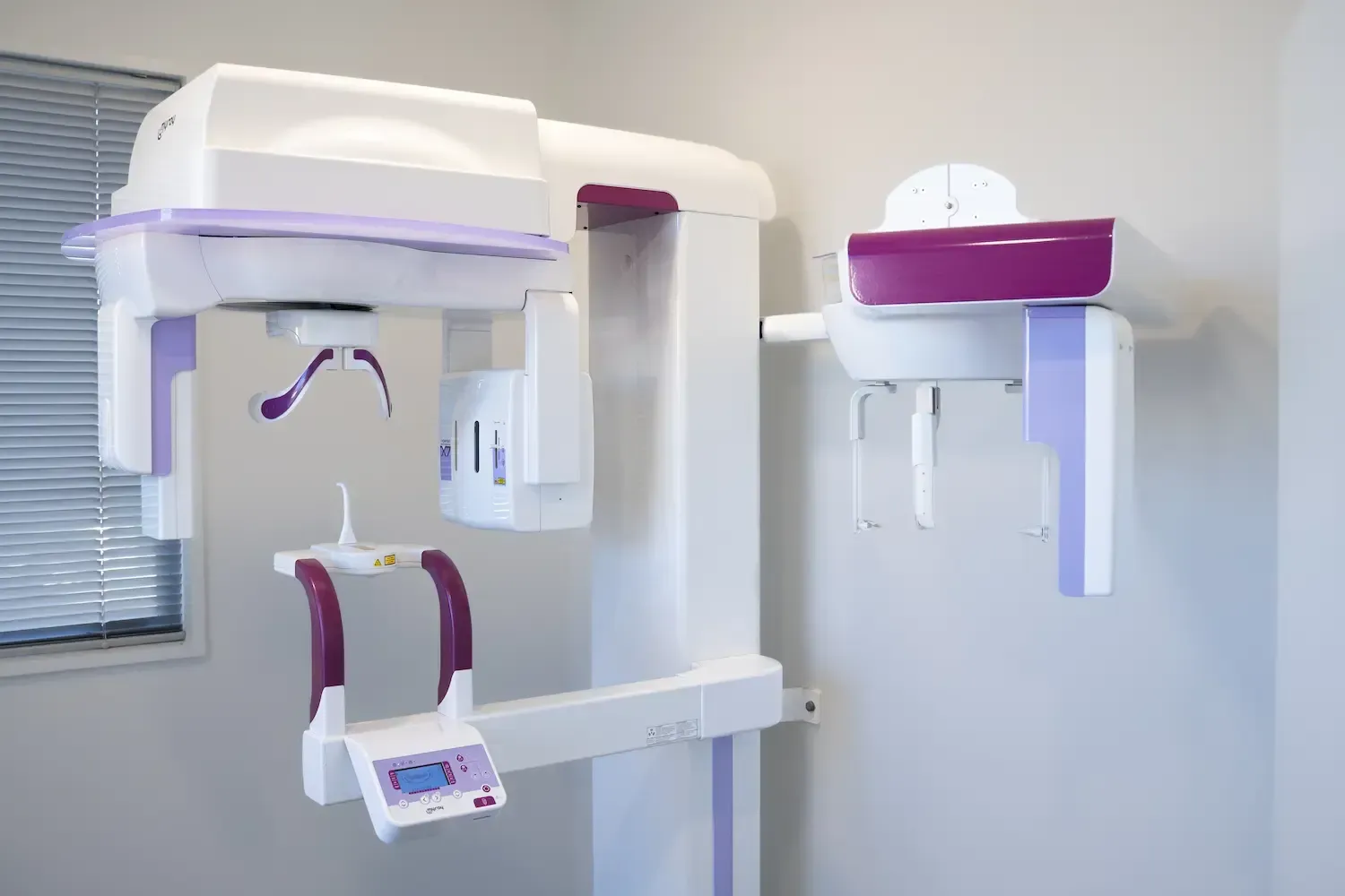 Dental panoramic X-ray machine, white and purple, in a dentist's office.