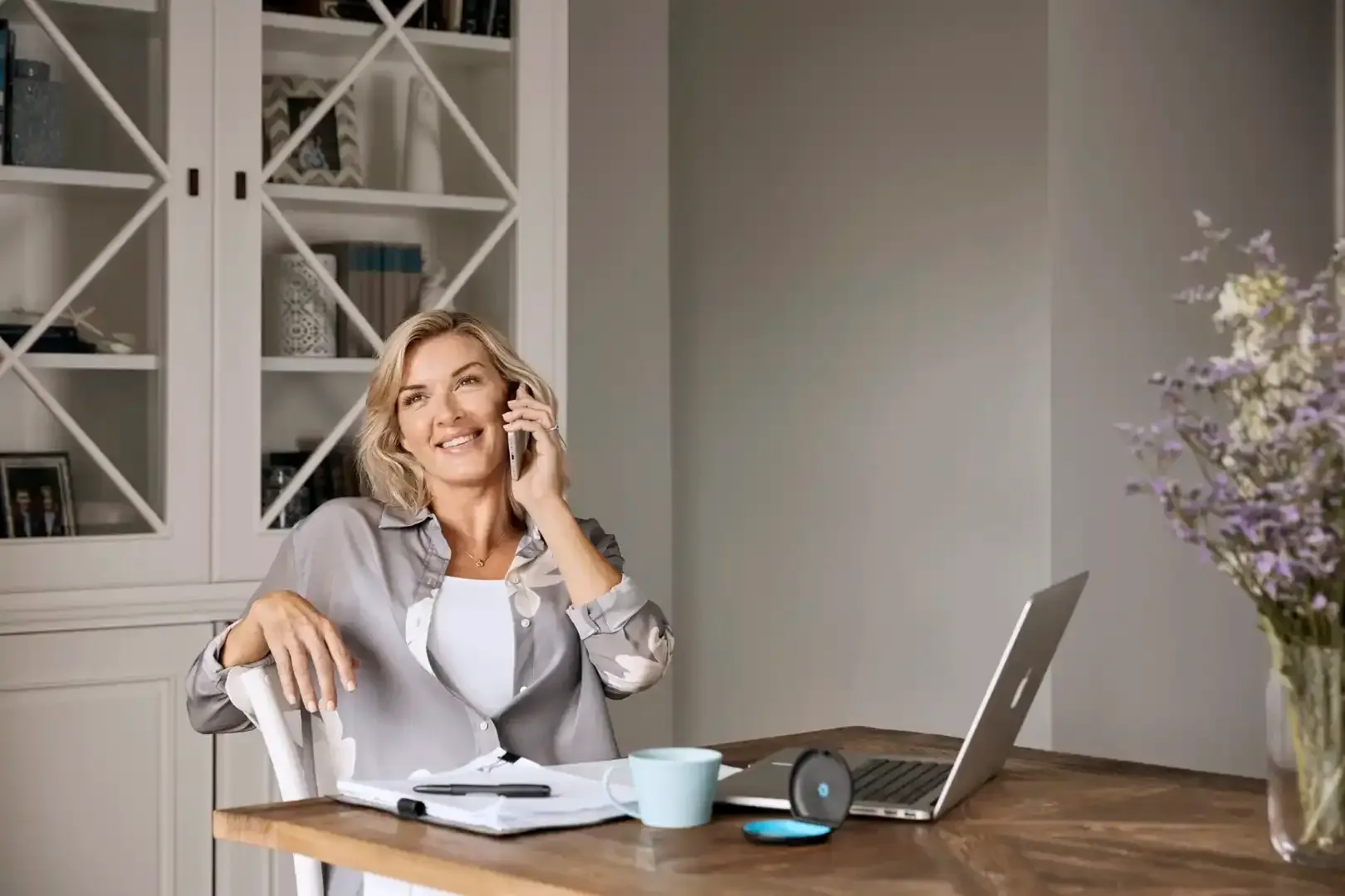 A woman is sitting at a desk talking on a cell phone.