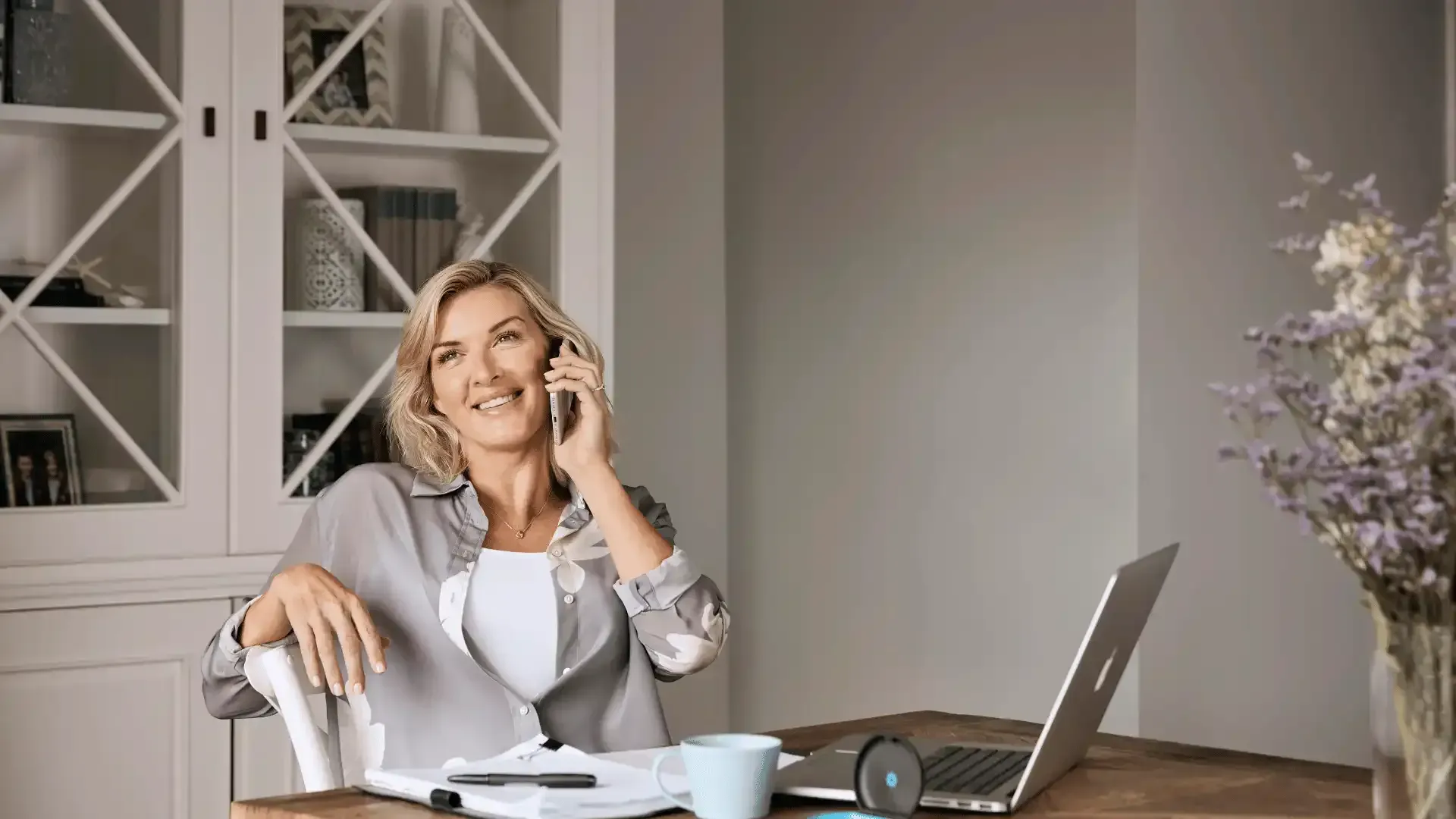 a woman is sitting at a desk talking on a cell phone .