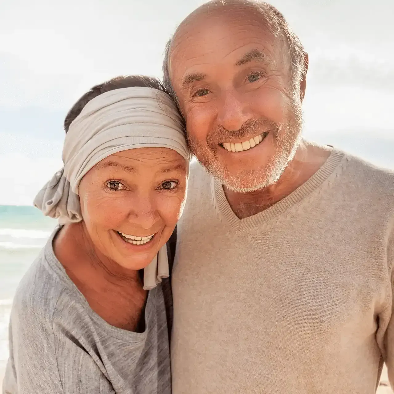 A man and a woman are posing for a picture on the beach.