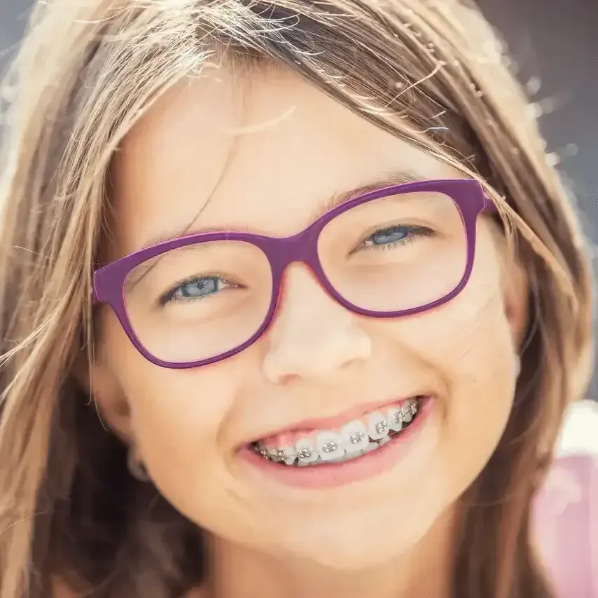 A young girl wearing glasses and braces is smiling for the camera.