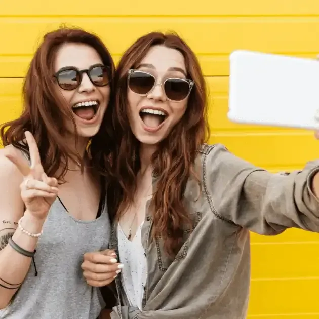 two women wearing sunglasses are taking a selfie together