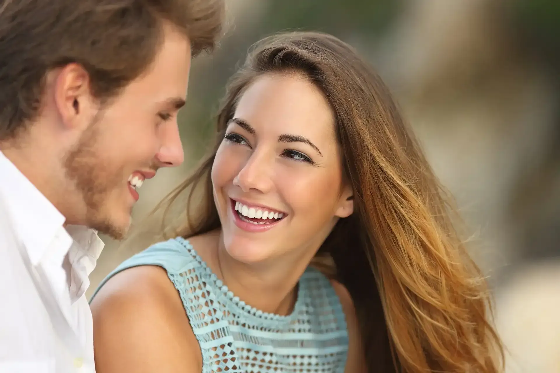a man and a woman are looking at each other and smiling .