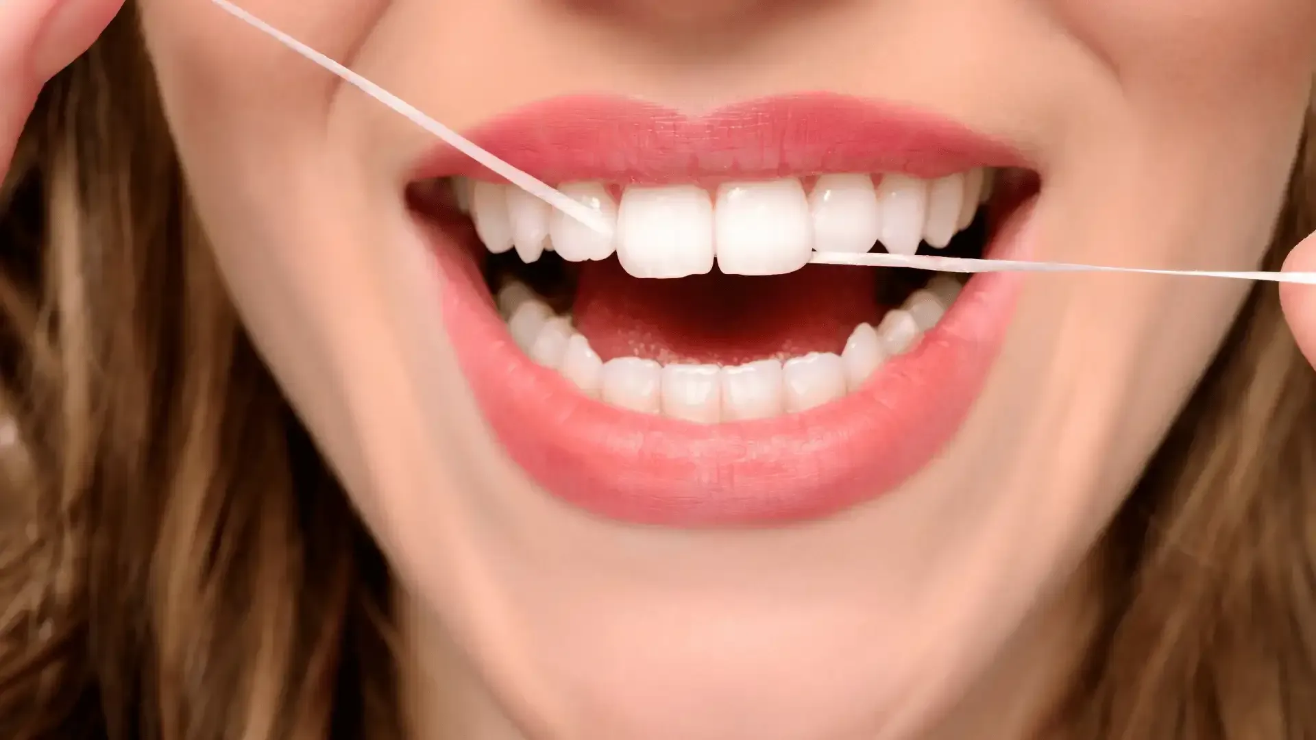 Flossing teeth a woman is flossing her teeth with a dental floss .