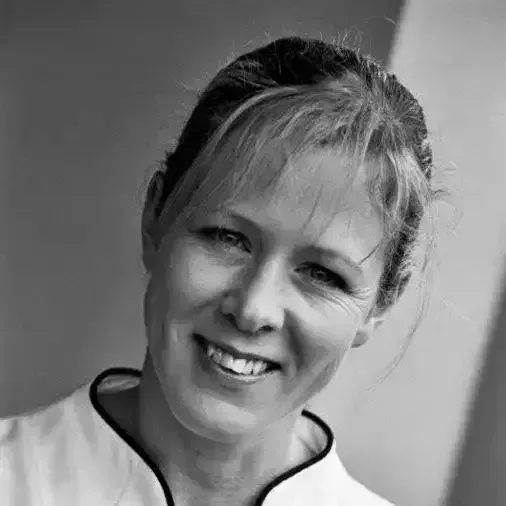 a woman in a white shirt is smiling in a black and white photo .