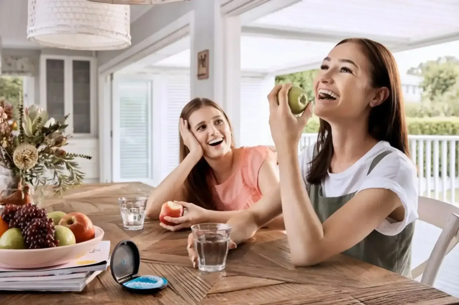 Young woman smiling about to eat an apple - Invisalign Christchurch