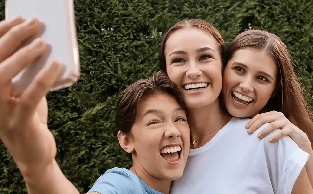 A woman is taking a selfie with her two daughters.