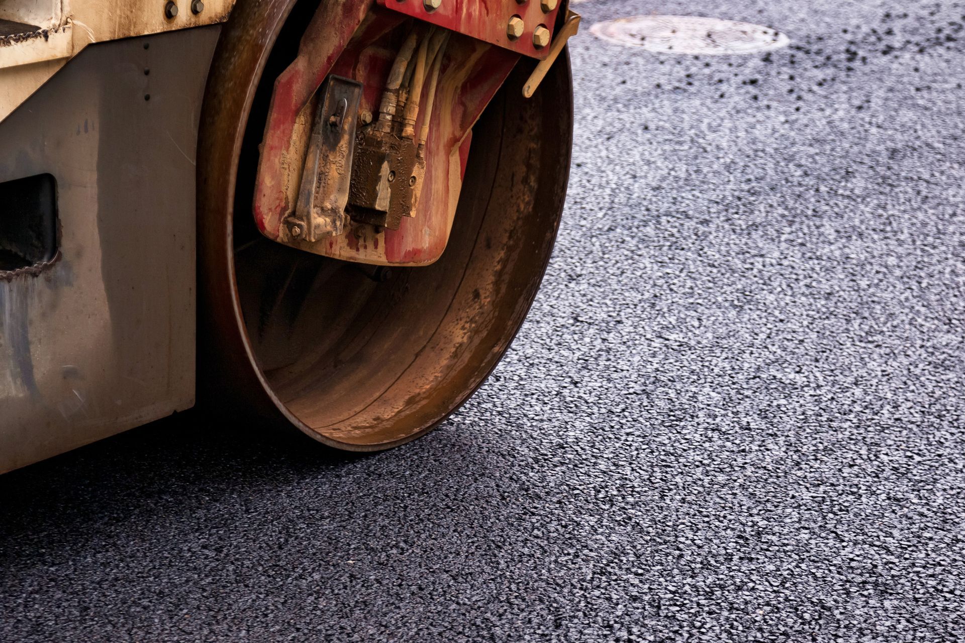 Industrial paving with asphalt roller compacting a fresh surface