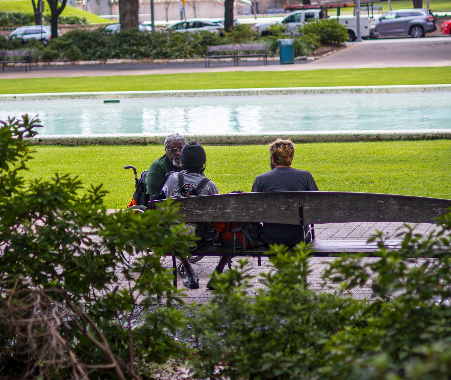A SMART team member speaks with two people seated on a park bench during street outreach.