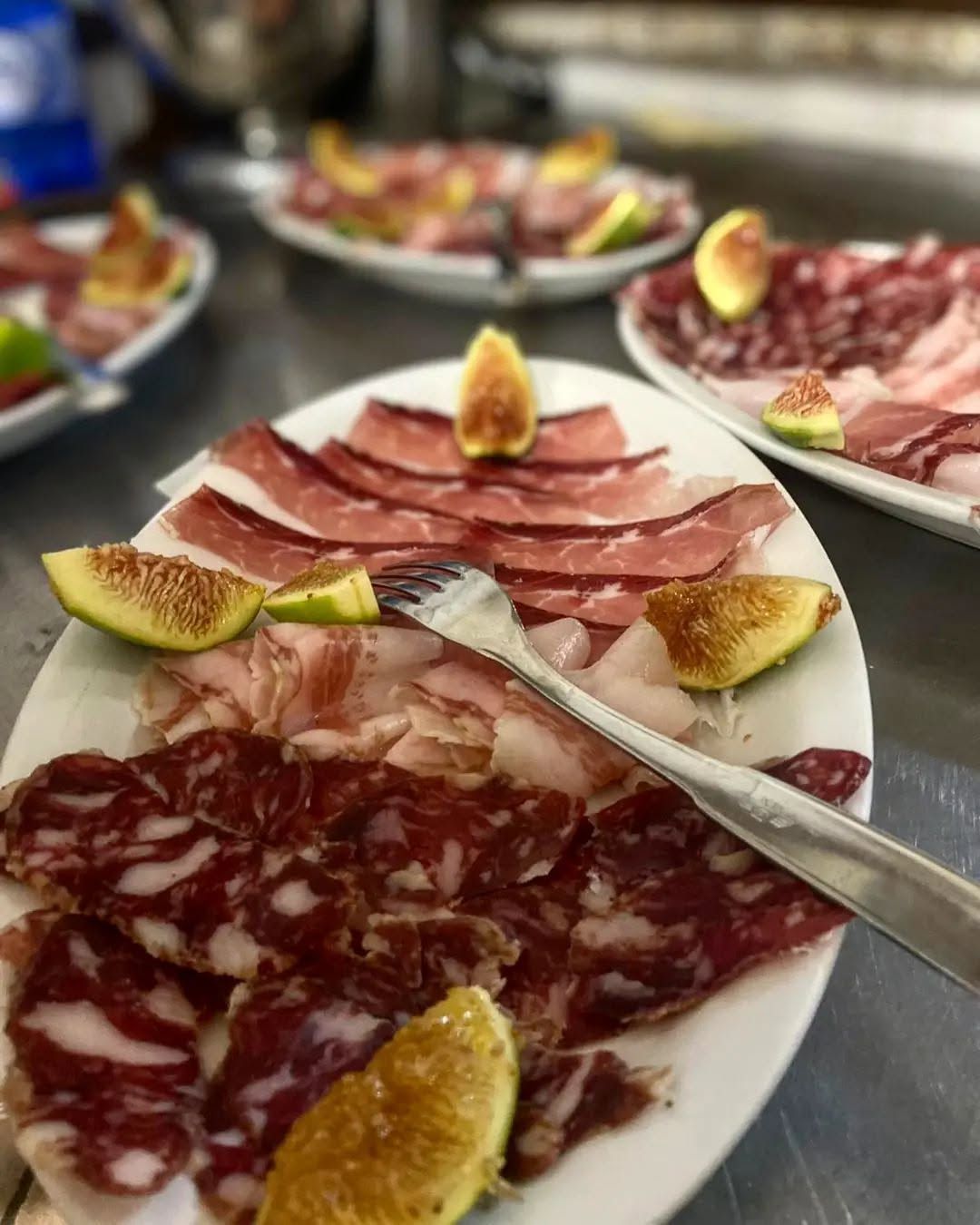 Un piatto di empanadas fritte a forma di mezzaluna, di colore marrone dorato, disposte su una tovaglia a quadri rossi e bianchi.