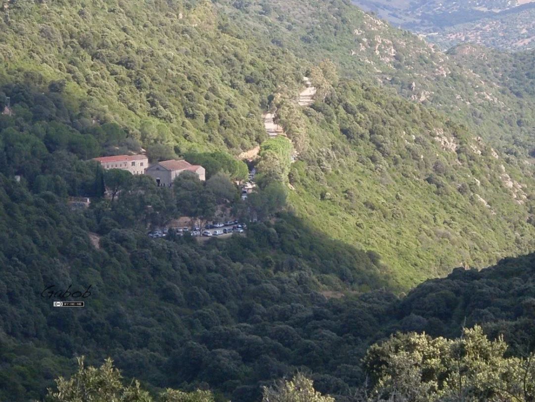 Edifici in pietra con tetti di terracotta immersi in una lussureggiante e verde vallata di montagna in una giornata di sole.