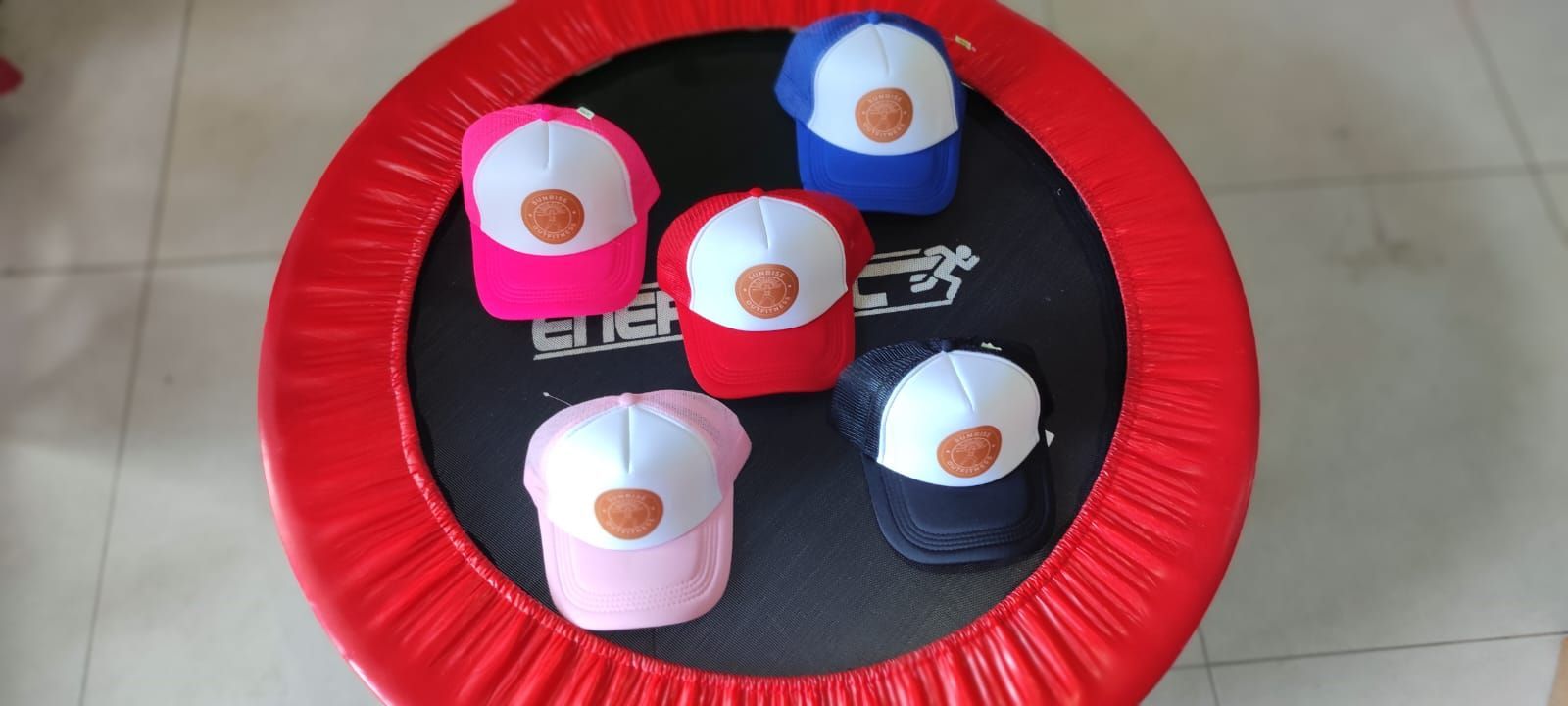 Una gorra de camionero rosa, blanca y marrón con un logotipo que dice 