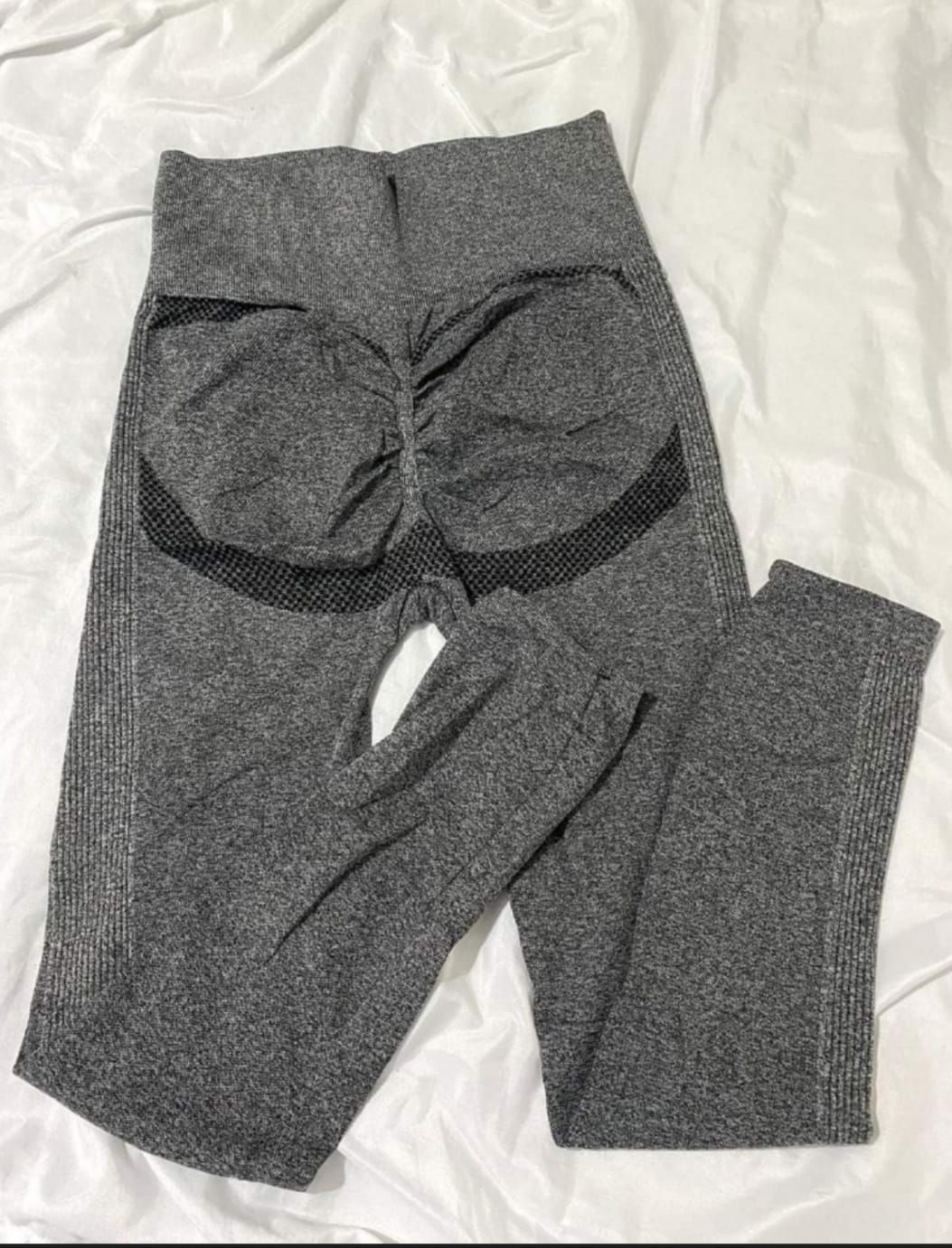 Leggings grises de entrenamiento con detalle fruncido en la parte trasera, sobre tela blanca.