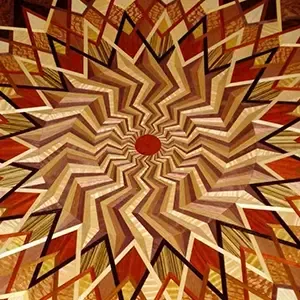 Abstract geometric starburst pattern in tan, brown, and red with a small red center circle