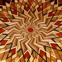 Abstract geometric starburst pattern in tan, brown, and red with a small red center circle