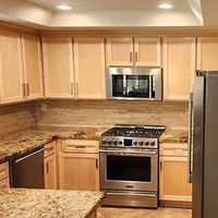 Modern kitchen with beige cabinets, granite counters, stainless steel appliances, and a gas range