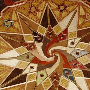 Abstract spiral mosaic with warm tan, brown, red, and cream geometric tiles.