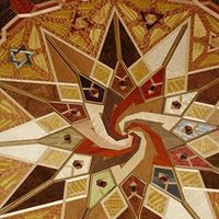 Abstract spiral mosaic with warm tan, brown, red, and cream geometric tiles.