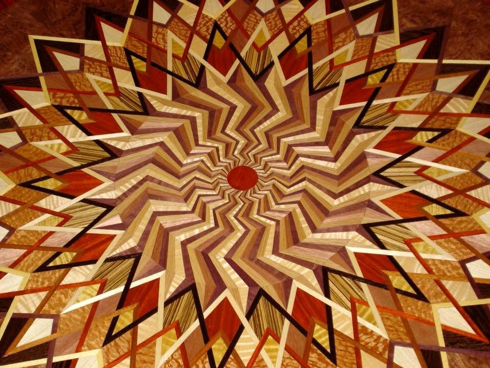 Abstract radial starburst pattern in warm orange, gold, and brown tones with zigzag geometric shapes