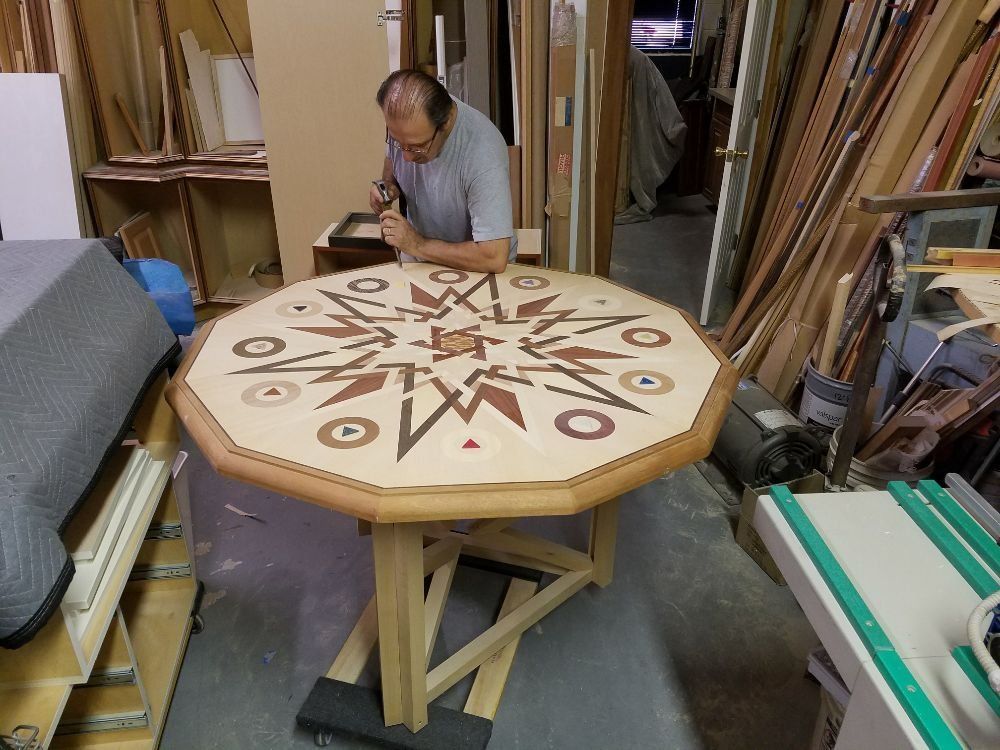 Octagonal table with decorative inlay, being worked on by a person in a woodworking shop